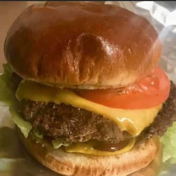 A Nephew's Steak & Hoagy cheeseburger with lettuce, tomato, and melted cheese on a brioche bun.